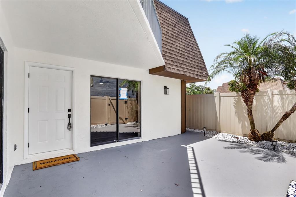 A white exterior door and sliding glass door open onto a gray concrete patio area — 4075 SHANNON BROWN DRIVE, ORLANDO, FL