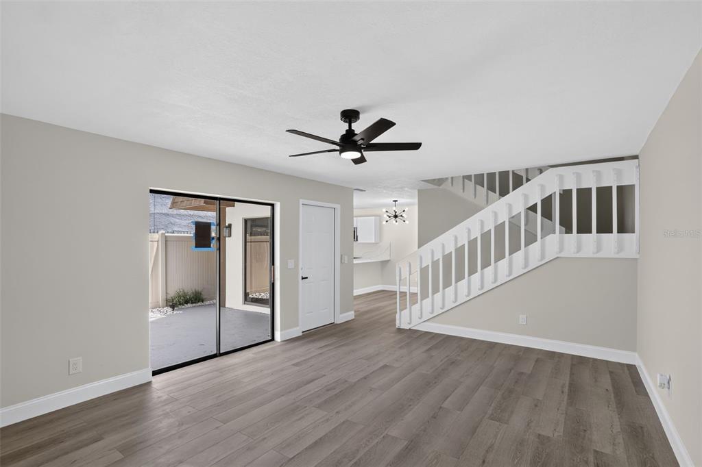 A living room with wood-look flooring, a ceiling fan, a staircase, and sliding glass doors — 4075 SHANNON BROWN DRIVE, ORLANDO, FL