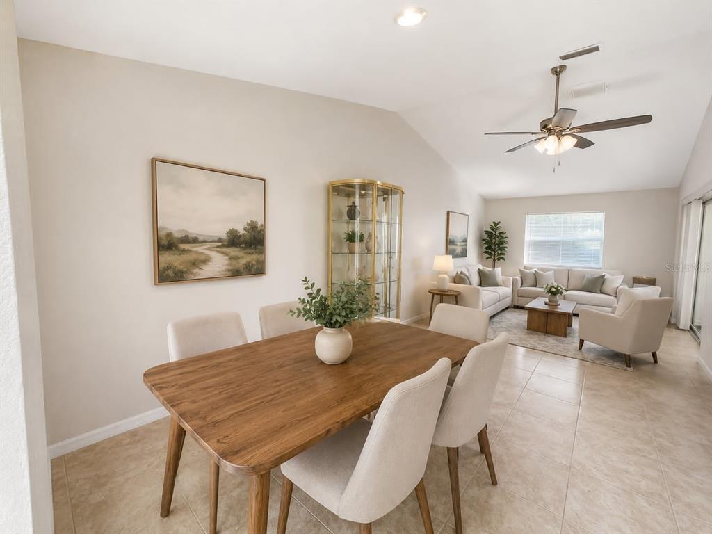 A dining area with a wooden table and chairs opens into a living room — 1203 SAXONY CIRCLE UNIT B, PUNTA GORDA, FL