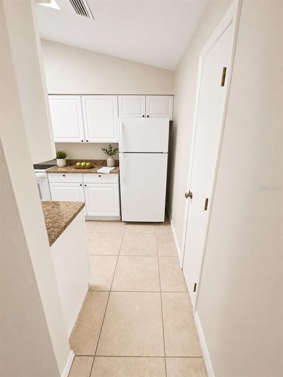 A galley kitchen features white cabinets, granite countertops, and stainless steel appliances — 1203 SAXONY CIRCLE UNIT B, PUNTA GORDA, FL
