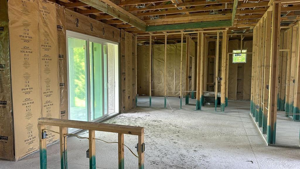 An unfinished room features exposed wooden wall studs, insulation, and a sliding glass door — 14024 WENZEL AVENUE, PORT CHARLOTTE, FL