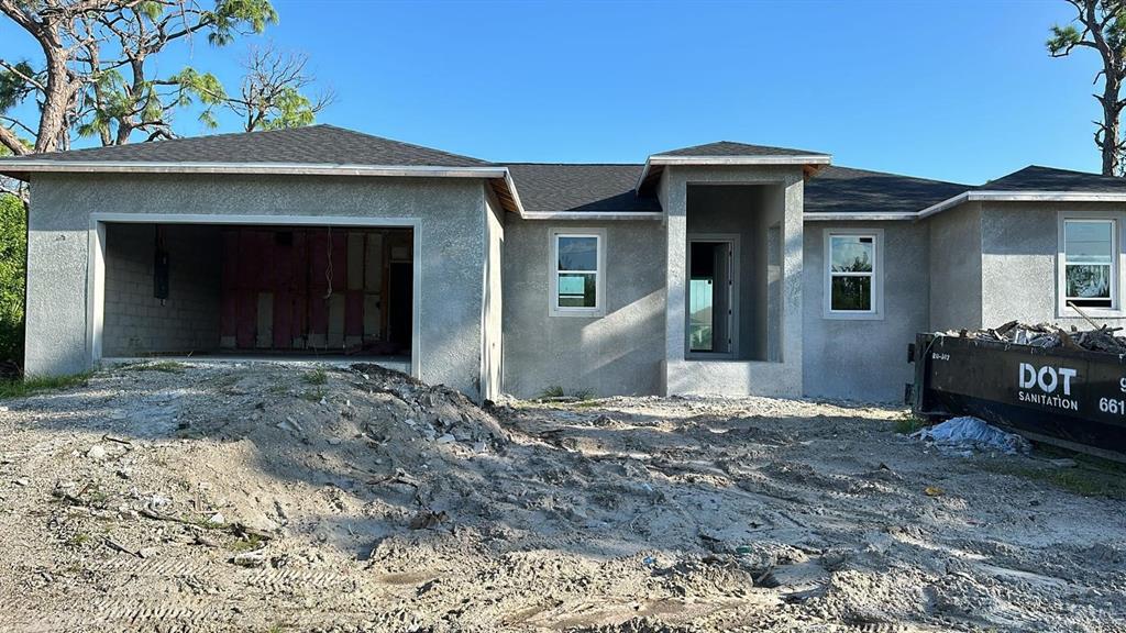 The exterior of a single-story house under construction features a garage, entryway, and stucco siding — 14024 WENZEL AVENUE, PORT CHARLOTTE, FL