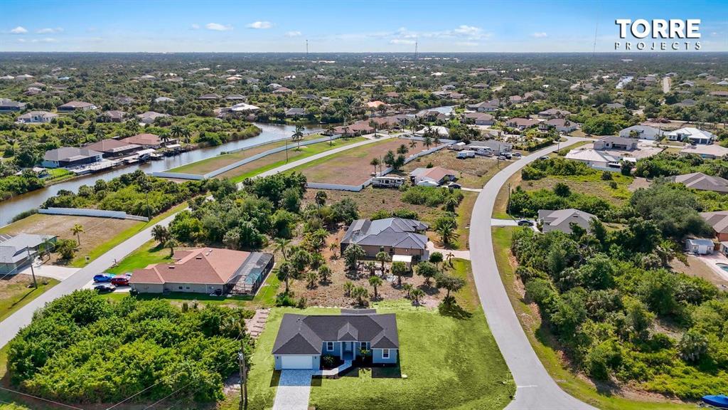 An aerial view shows a single-story house with a dark roof and a paved driveway — 14024 WENZEL AVENUE, PORT CHARLOTTE, FL