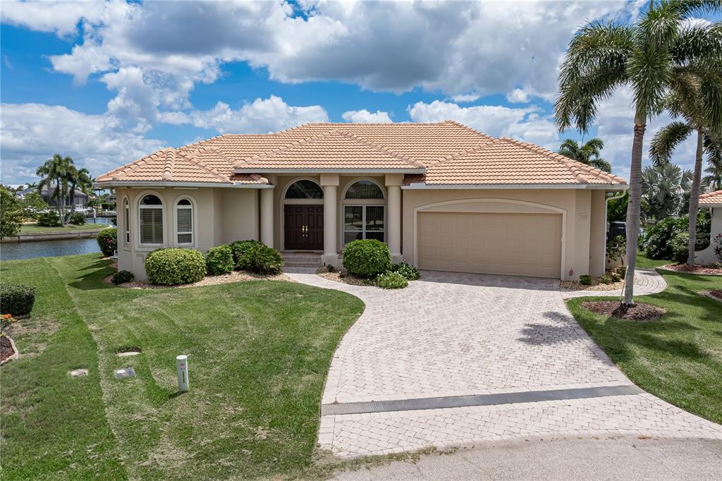 A single-story house with a tile roof, paved driveway, and palm trees in a residential neighborhood — 3366 TRINIDAD COURT, PUNTA GORDA, FL