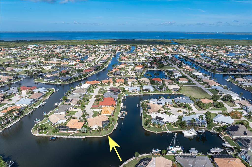 An aerial view shows a waterfront house with a pool cage on a canal corner — 3366 TRINIDAD COURT, PUNTA GORDA, FL