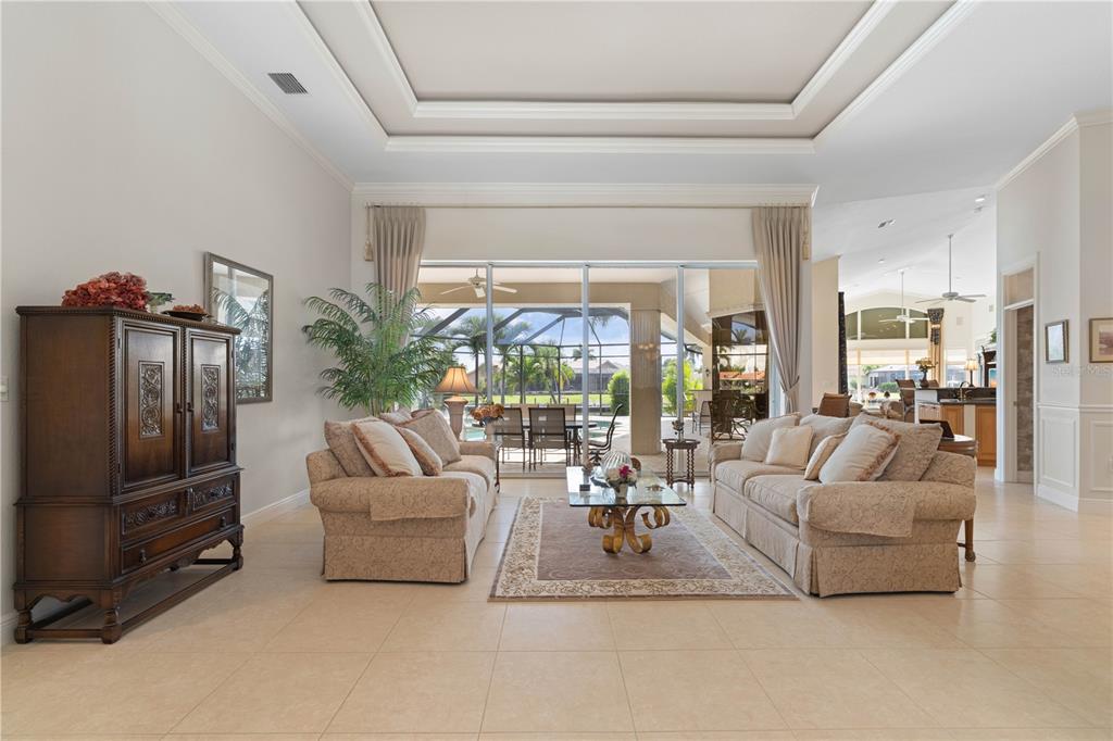A living room features two beige sofas, a glass coffee table, and large sliding glass doors — 3366 TRINIDAD COURT, PUNTA GORDA, FL