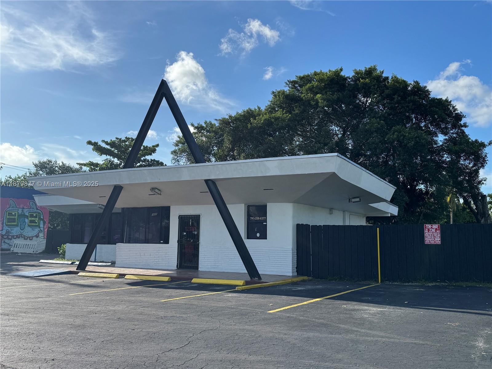 A white commercial building features a prominent black A-frame support structure and a parking lot — 1605 NW 95th St, Miami FL 33147, MIAMI, FL