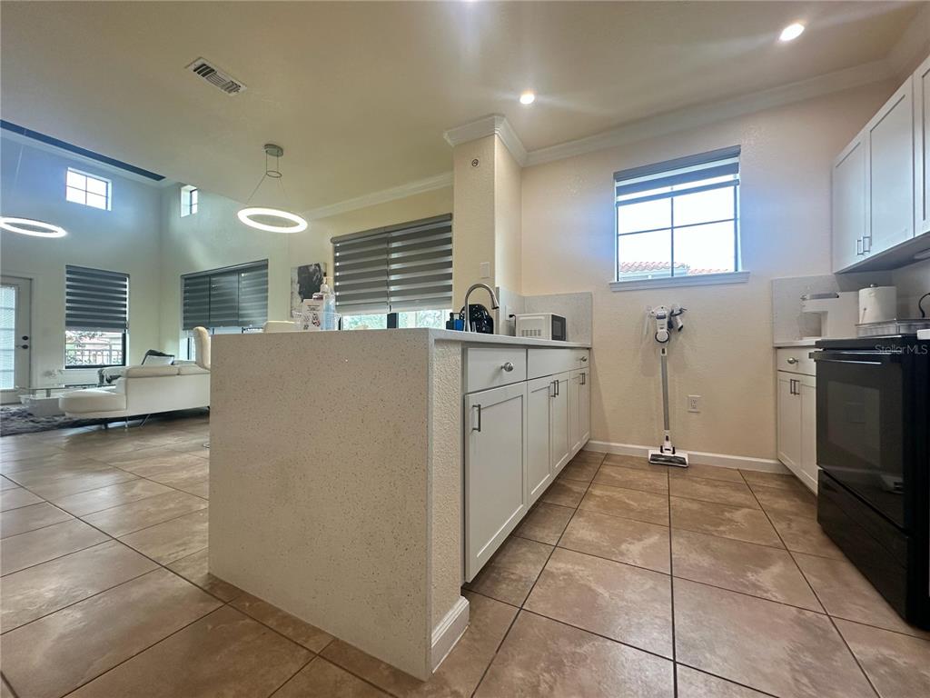 A kitchen with white cabinets, a stone-topped island, and tile flooring overlooks a living area — 903 CHARO PARKWAY UNIT 837, DAVENPORT, FL
