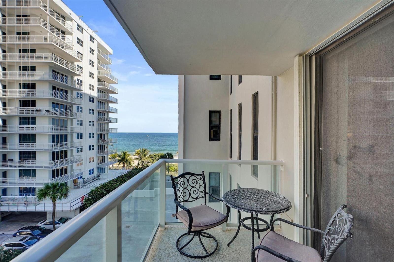 A balcony with a small table and two chairs overlooks the ocean and nearby buildings — 1000 S Ocean Boulevard # 6m, Pompano Beach FL 33062, POMPANO BEACH, FL