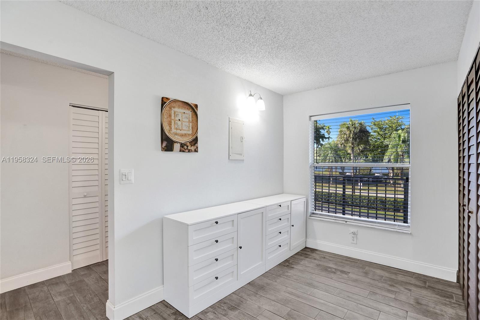 A room with white walls, wood-look flooring, a built-in dresser, and a window view — 4570 NW 18th Avenue # 202, Deerfield Beach FL 33064, DEERFIELD BEACH, FL