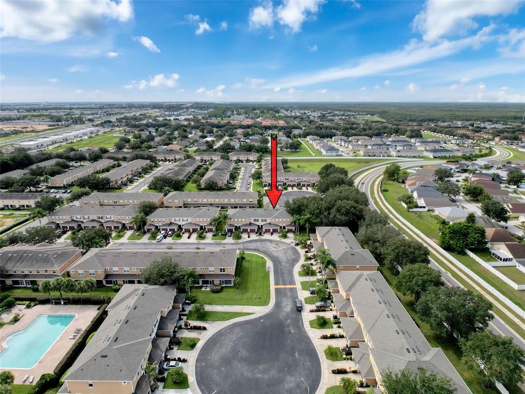 An aerial view shows a residential complex with townhomes, a swimming pool, and roads — 335 BEXLEY DRIVE, DAVENPORT, FL