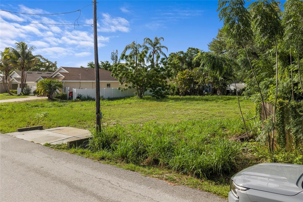 A vacant, grassy lot sits next to a paved road with trees in the background — 2930 HAWTHORNE STREET, SARASOTA, FL