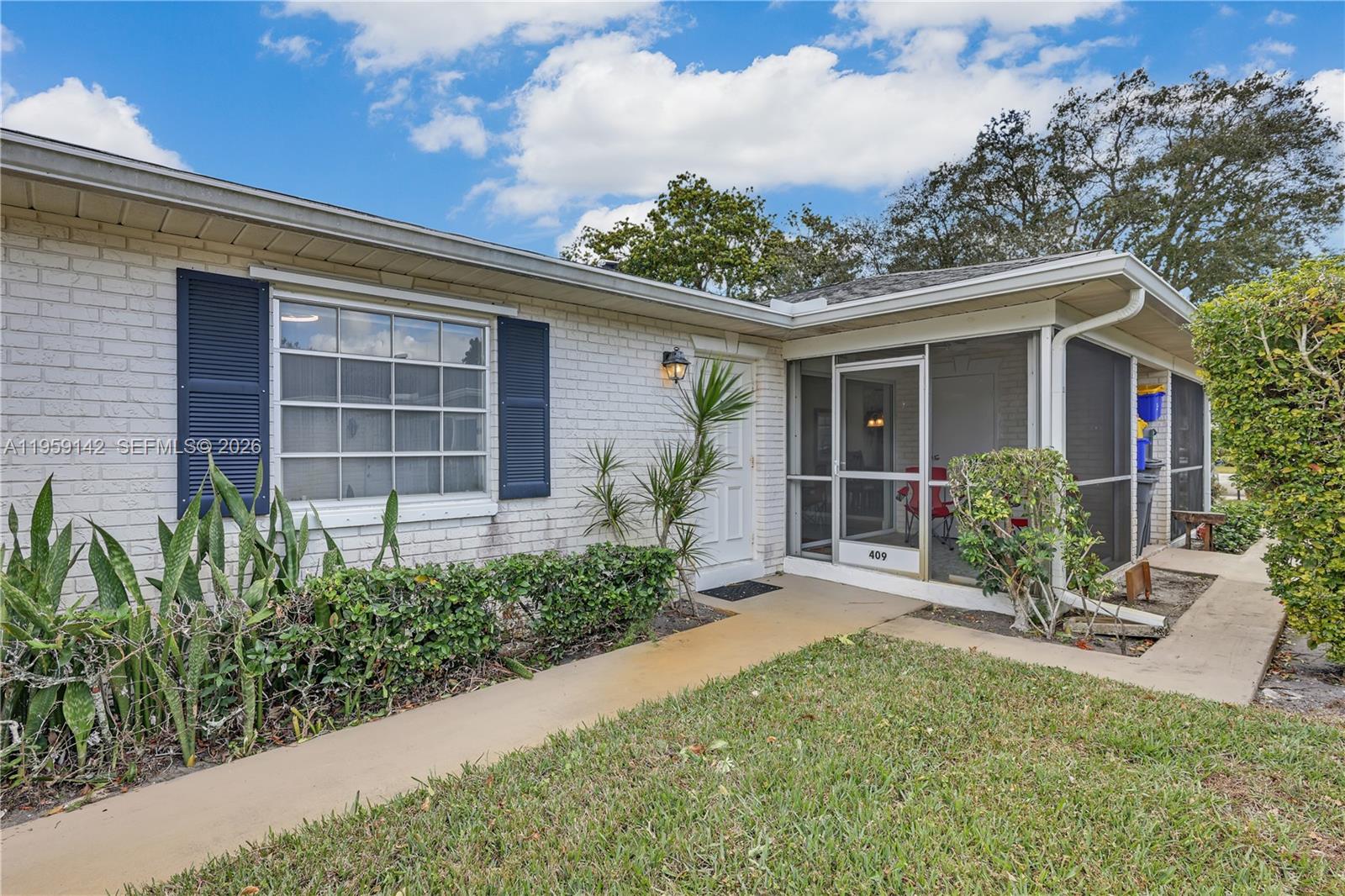 A white brick house features blue shutters, a screened-in porch, and a concrete walkway — 10115 44th Way S # 409, Boynton Beach FL 33436, BOYNTON BEACH, FL