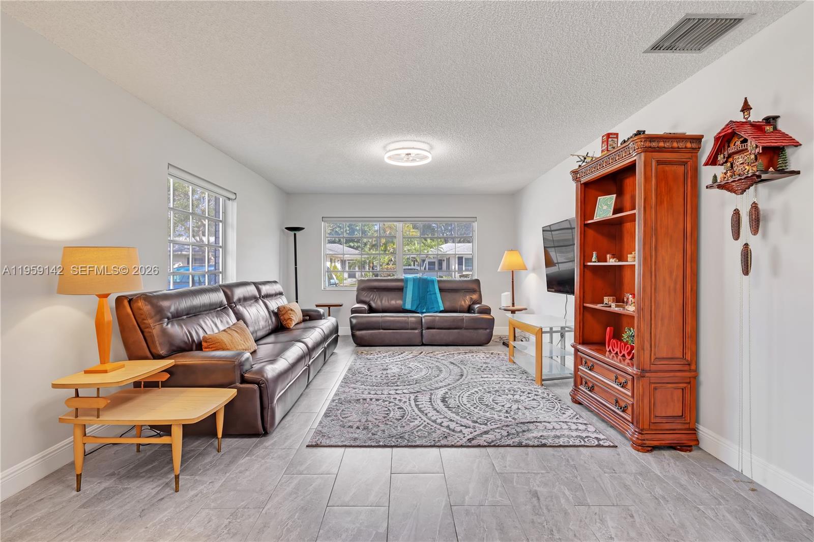 A living room features gray tile flooring, two brown leather sofas, and a wooden hutch — 10115 44th Way S # 409, Boynton Beach FL 33436, BOYNTON BEACH, FL