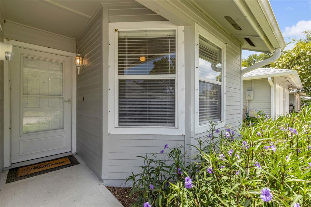 A light gray house exterior features a white front door, bay windows, and purple flowers — 937 MEADOW VIEW DRIVE UNIT B, PORT ORANGE, FL