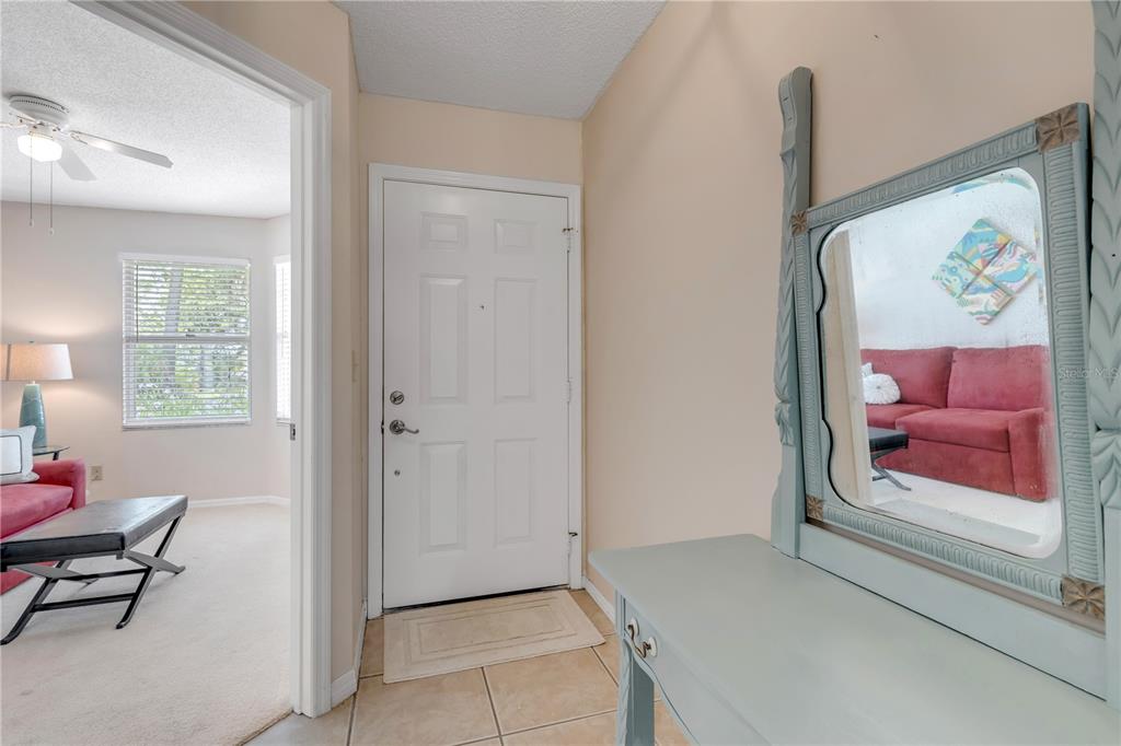 An entryway features a white door, tile flooring, and a light blue vanity with a mirror — 937 MEADOW VIEW DRIVE UNIT B, PORT ORANGE, FL