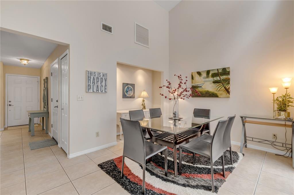 A dining room features a glass table, dark chairs, a patterned rug, and high ceilings — 937 MEADOW VIEW DRIVE UNIT B, PORT ORANGE, FL
