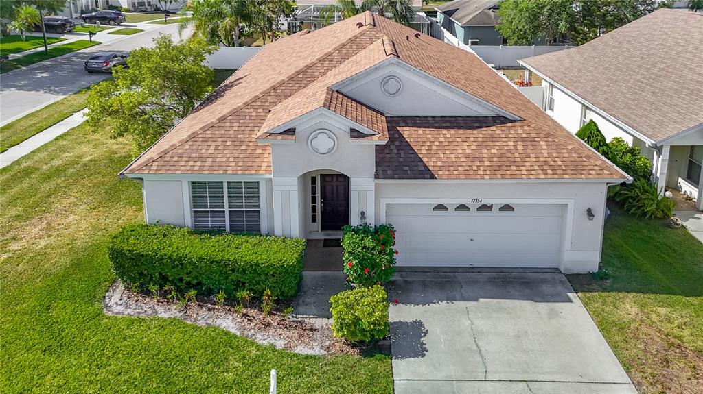An aerial view of a single-story suburban house with a brown shingled roof and garage — 17354 LAWN ORCHID LOOP, LAND O LAKES, FL