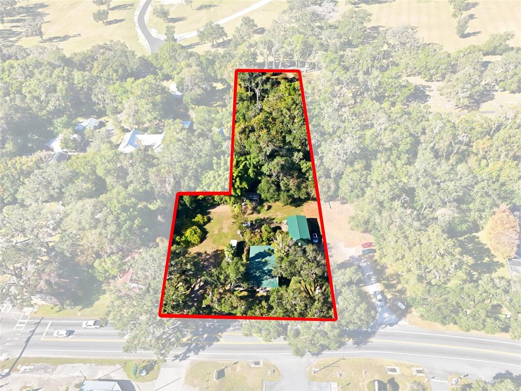 An aerial view shows a residential property with two buildings surrounded by trees and vegetation — 7698 S FLORIDA AVENUE UNIT 1, FLORAL CITY, FL