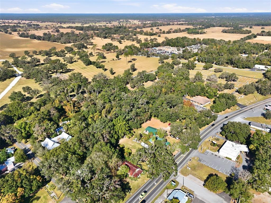 An aerial view shows a wooded property with several buildings, a road, and surrounding fields — 7698 S FLORIDA AVENUE UNIT 1, FLORAL CITY, FL