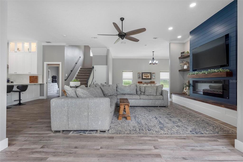 A living room features a blue shiplap fireplace, gray sectional sofa, and wood-look flooring — 1079 RIVERSIDE RIDGE ROAD, TARPON SPRINGS, FL