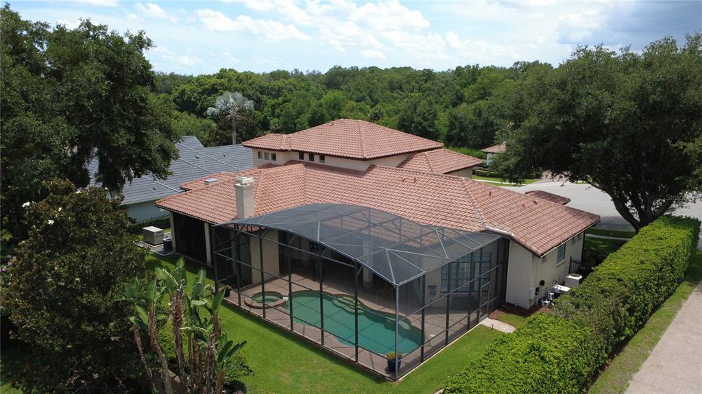 An aerial view of a house with a tiled roof, screened pool, and surrounding trees — 3318 SUNSET VIEW COURT, LONGWOOD, FL