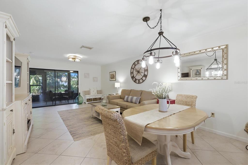A bright living and dining area features tile floors, a round table, and a sofa — 106 JOSE GASPAR DRIVE UNIT 106, ENGLEWOOD, FL