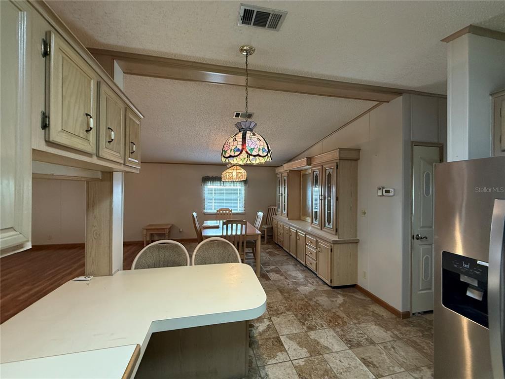 A kitchen with light wood cabinets, a breakfast bar, and a dining area with tile flooring — 805 OAK BOULEVARD, WILDWOOD, FL
