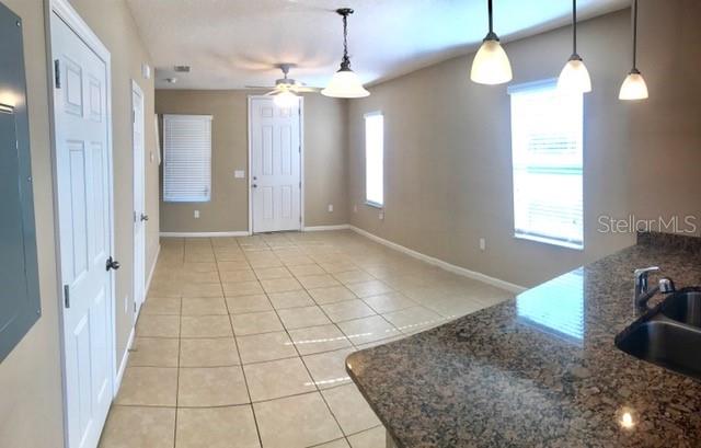 A kitchen island with a granite countertop overlooks an open-concept living area with tile floors — 1102 CHELSEA DRIVE, DAVENPORT, FL