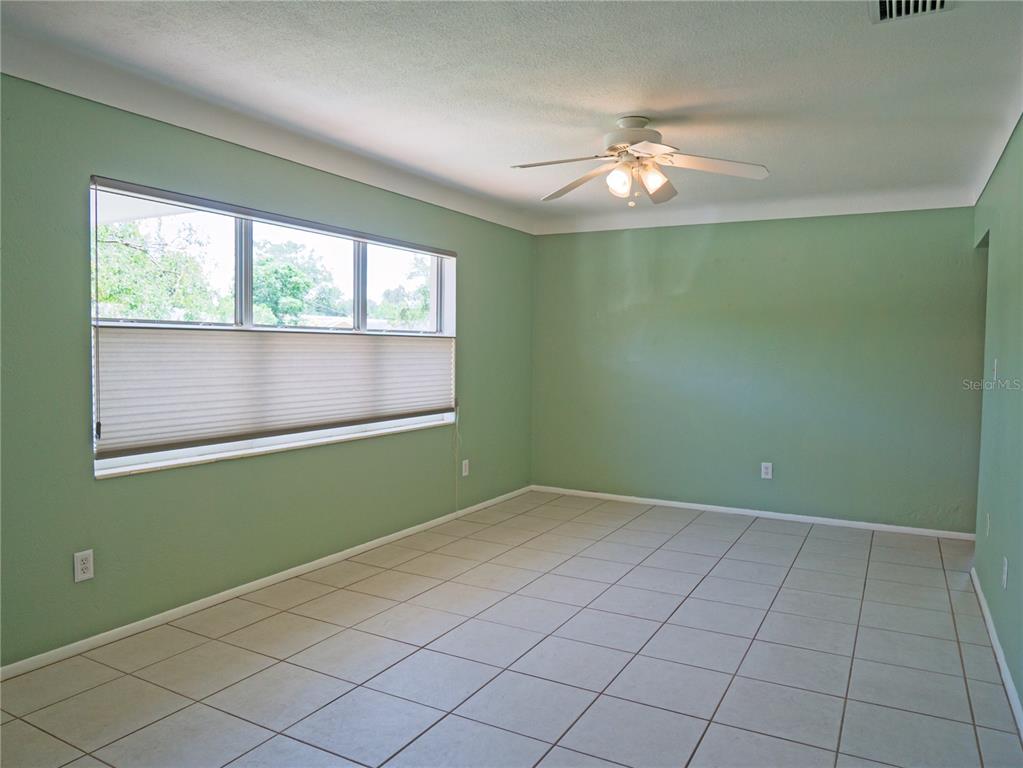 An empty room features light green walls, white tile flooring, and a ceiling fan — 6724 17TH LANE N, ST PETERSBURG, FL