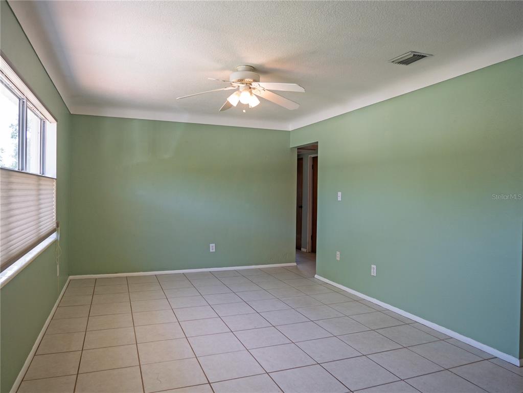 A room with light green walls, a white ceiling fan, and light-colored tile flooring — 6724 17TH LANE N, ST PETERSBURG, FL