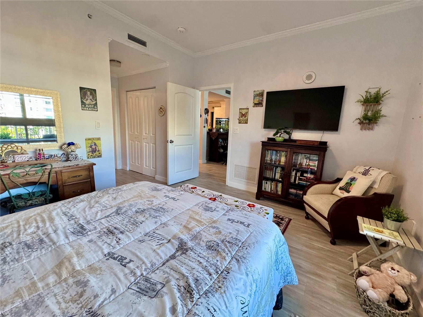 A bedroom features a bed with a Paris-themed quilt, a television, and a wooden bookcase — 7355 SW 89th St # 423N, Miami FL 33156, MIAMI, FL