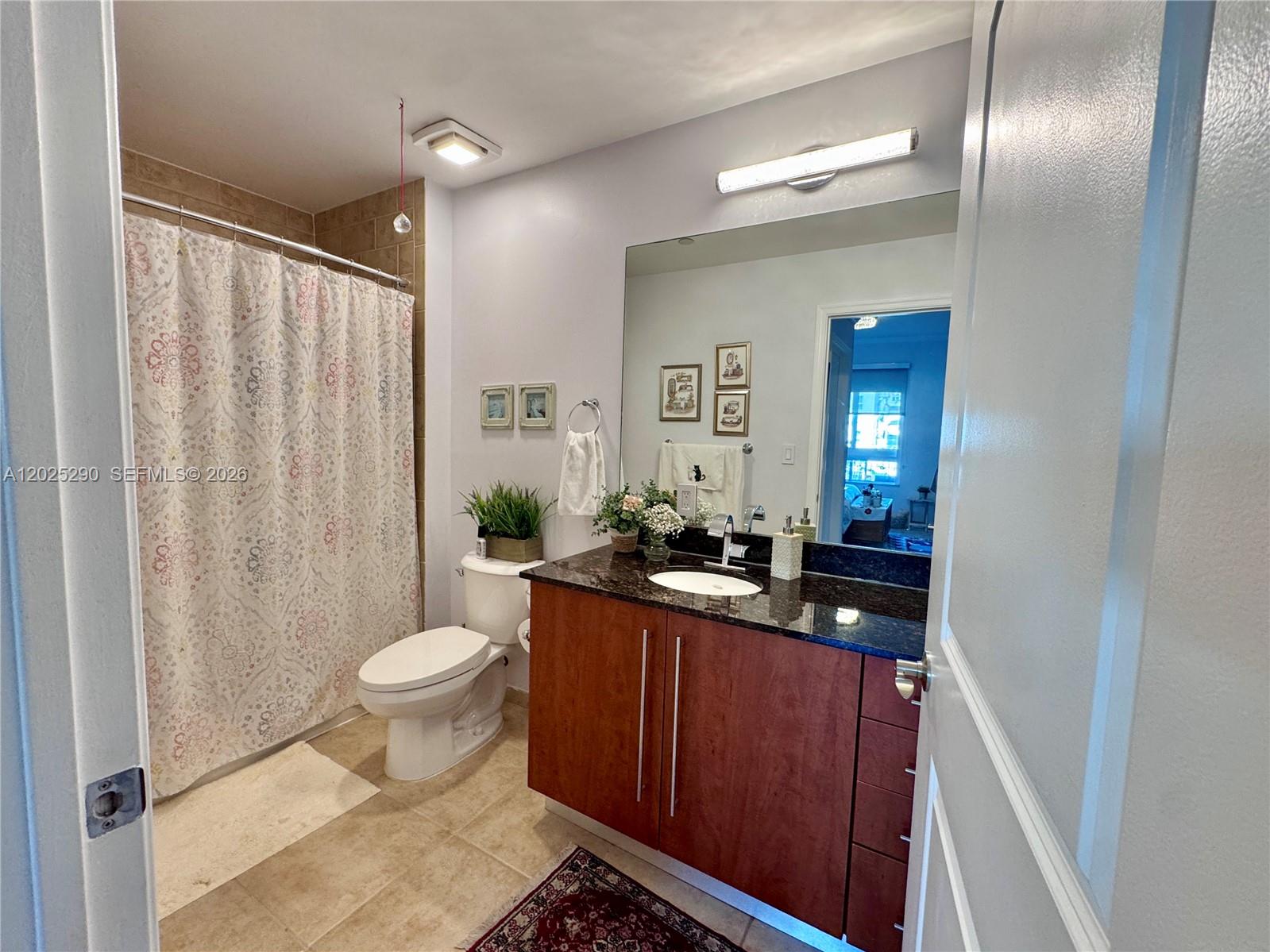 A bathroom features a wood vanity with a dark countertop, a toilet, and a shower curtain — 7355 SW 89th St # 423N, Miami FL 33156, MIAMI, FL