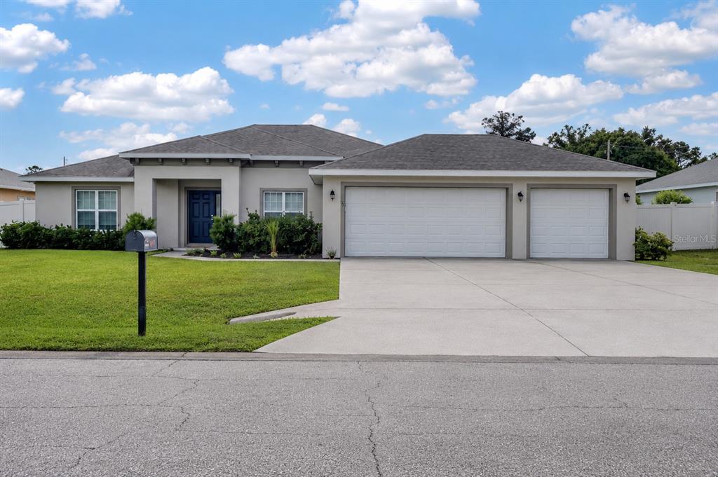 A single-story house with a three-car garage, gray roof, and a blue front door — 5 LYNTON PLACE, PALM COAST, FL