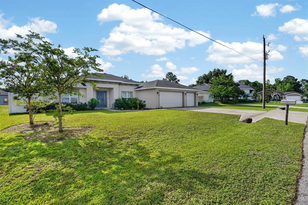 A single-story house with a beige exterior, a three-car garage, and a large front lawn — 5 LYNTON PLACE, PALM COAST, FL