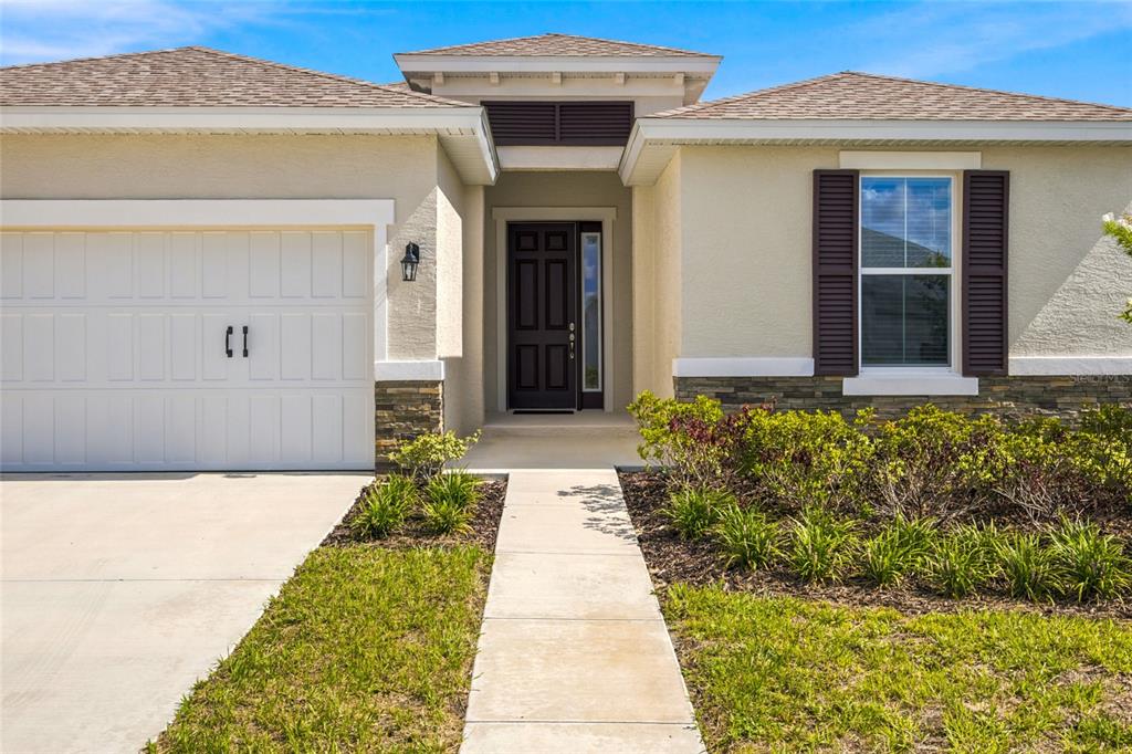 A single-story house exterior with a garage, front walkway, and a dark-framed front door — 7227 SW 58TH PLACE ROAD, OCALA, FL