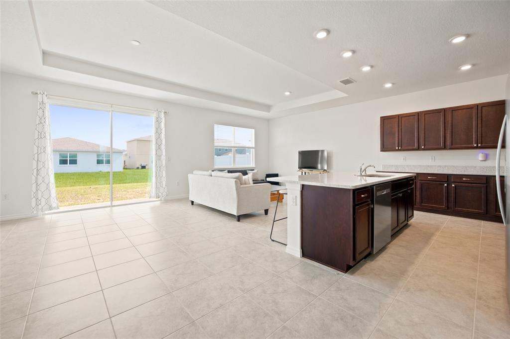 An open-concept kitchen and living area featuring dark wood cabinets, a kitchen island, and tile flooring — 7227 SW 58TH PLACE ROAD, OCALA, FL