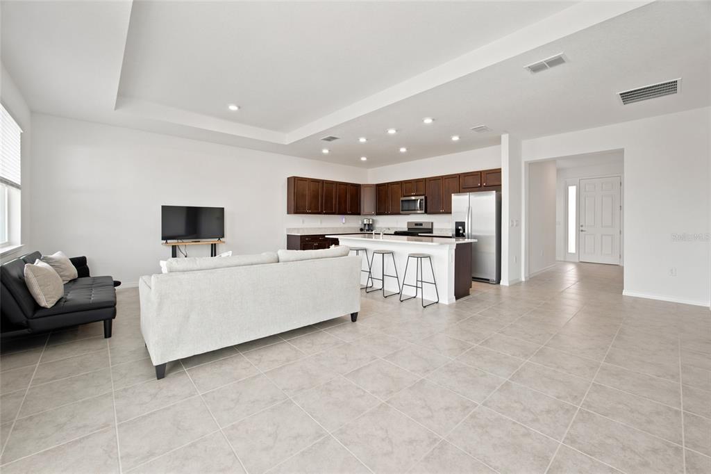 An open-concept living room and kitchen feature tile flooring, dark wood cabinets, and white walls — 7227 SW 58TH PLACE ROAD, OCALA, FL