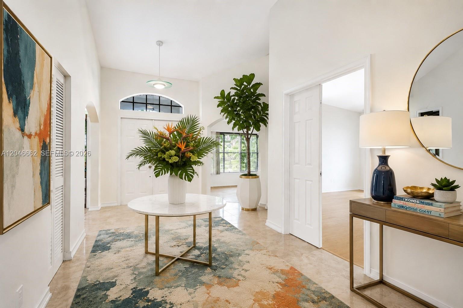 A bright foyer features a marble-topped table, a large area rug, and a tall plant — 3450 Dunes Vista Dr, Pompano Beach FL 33069, POMPANO BEACH, FL
