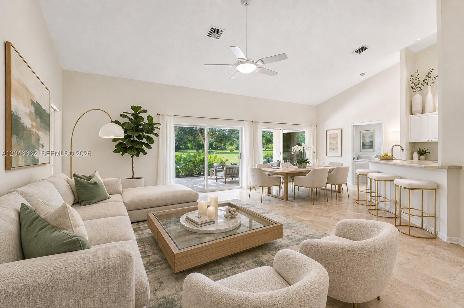 A bright, open-concept living and dining area features neutral furniture, tile floors, and sliding doors — 3450 Dunes Vista Dr, Pompano Beach FL 33069, POMPANO BEACH, FL