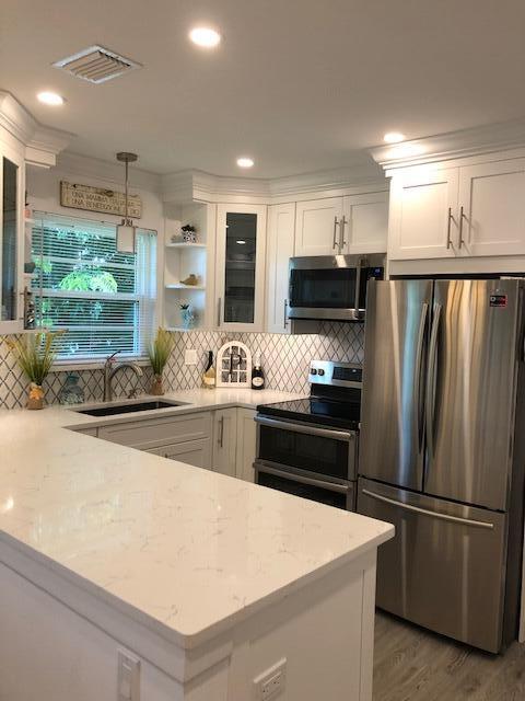 A modern kitchen features white cabinets, quartz countertops, stainless steel appliances, and a tiled backsplash — 2600 SE Ocean Boulevard # Q8, Stuart FL 34996, STUART, FL