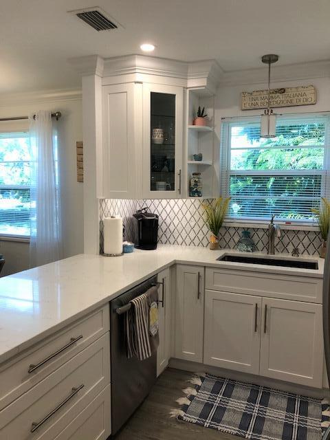 A white kitchen features quartz countertops, a tiled backsplash, and a stainless steel dishwasher — 2600 SE Ocean Boulevard # Q8, Stuart FL 34996, STUART, FL