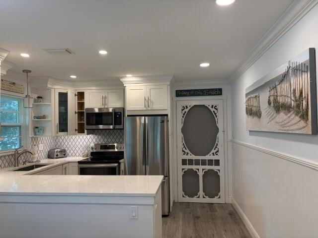 A kitchen features white cabinetry, stainless steel appliances, a tiled backsplash, and a screen door — 2600 SE Ocean Boulevard # Q8, Stuart FL 34996, STUART, FL