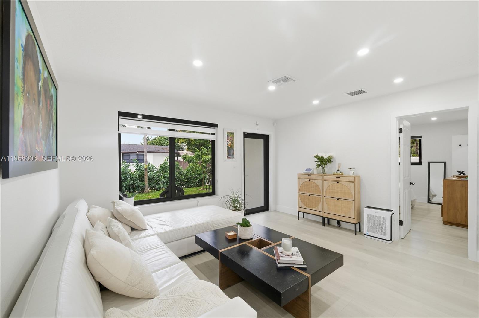 A bright living room features a white sectional sofa, a black coffee table, and light flooring — 7491 Raleigh St, Hollywood FL 33024, HOLLYWOOD, FL