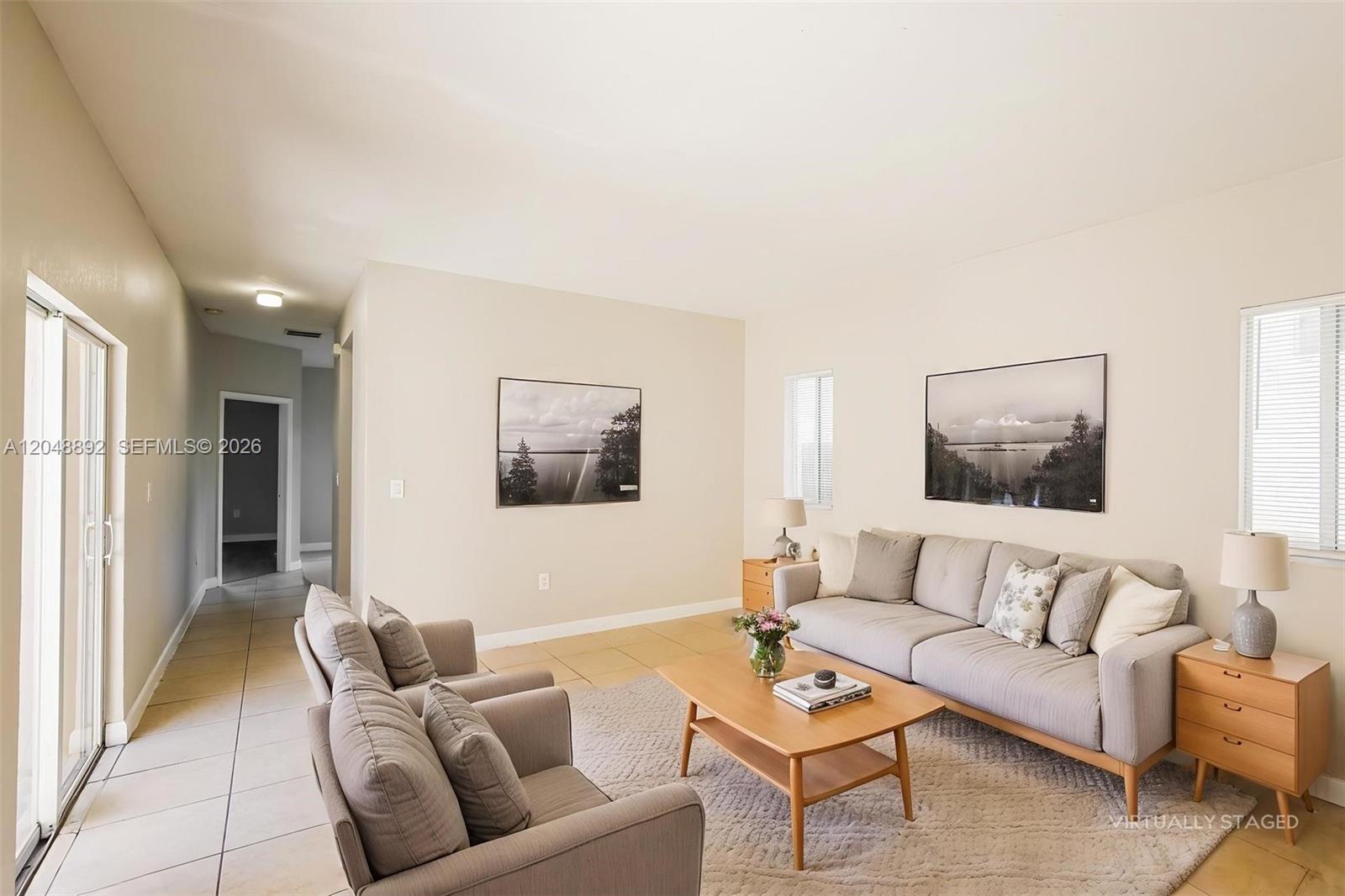This living room features tile flooring, a gray sofa, two armchairs, and two wall-mounted pictures — 216 SE 32nd Ter, Homestead FL 33033, HOMESTEAD, FL