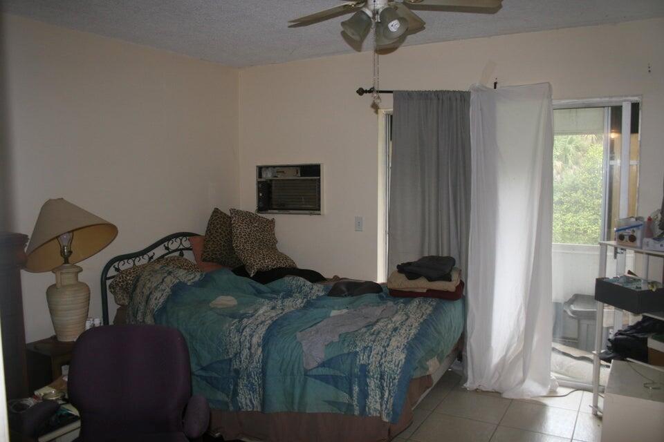 A bedroom with a bed, ceiling fan, wall air conditioner, and sliding glass door — 28 Camden B, West Palm Beach FL 33417, WEST PALM BEACH, FL