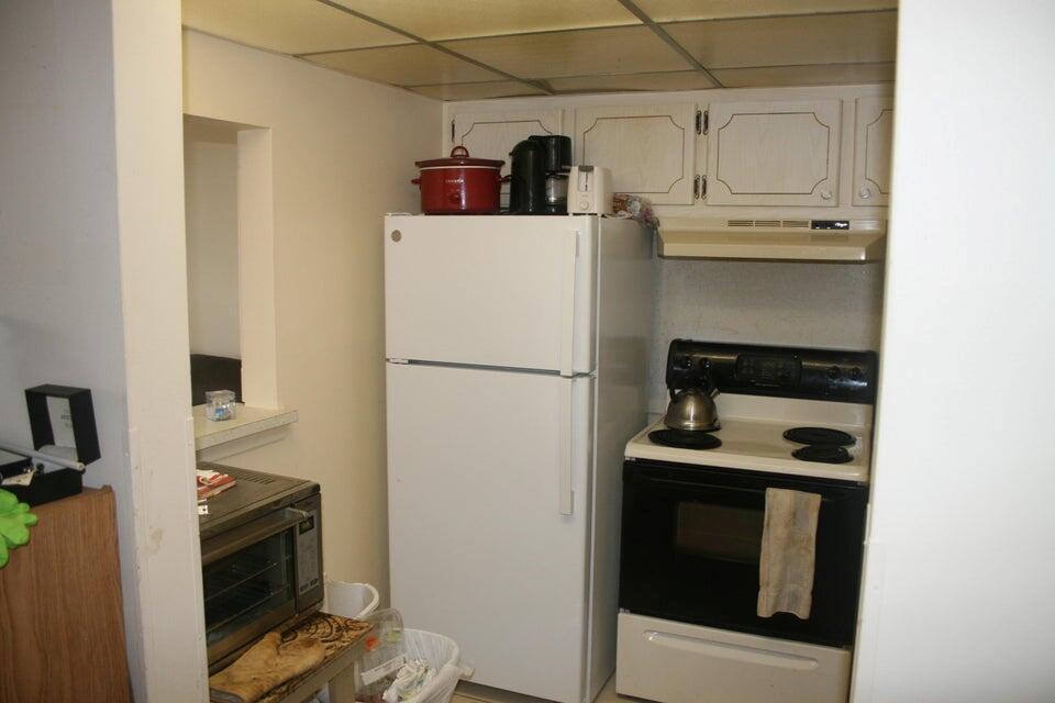 A kitchen features a white refrigerator, a black stove, and upper cabinets with wood trim — 28 Camden B, West Palm Beach FL 33417, WEST PALM BEACH, FL
