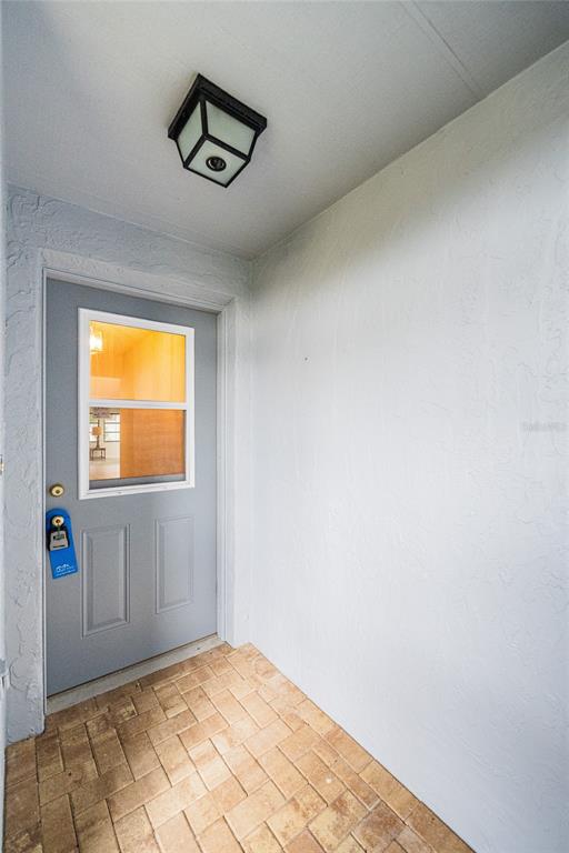 A gray door with a window and a lockbox opens onto a brick entryway — 4114 FISHERMANS LANDING, WINTER HAVEN, FL
