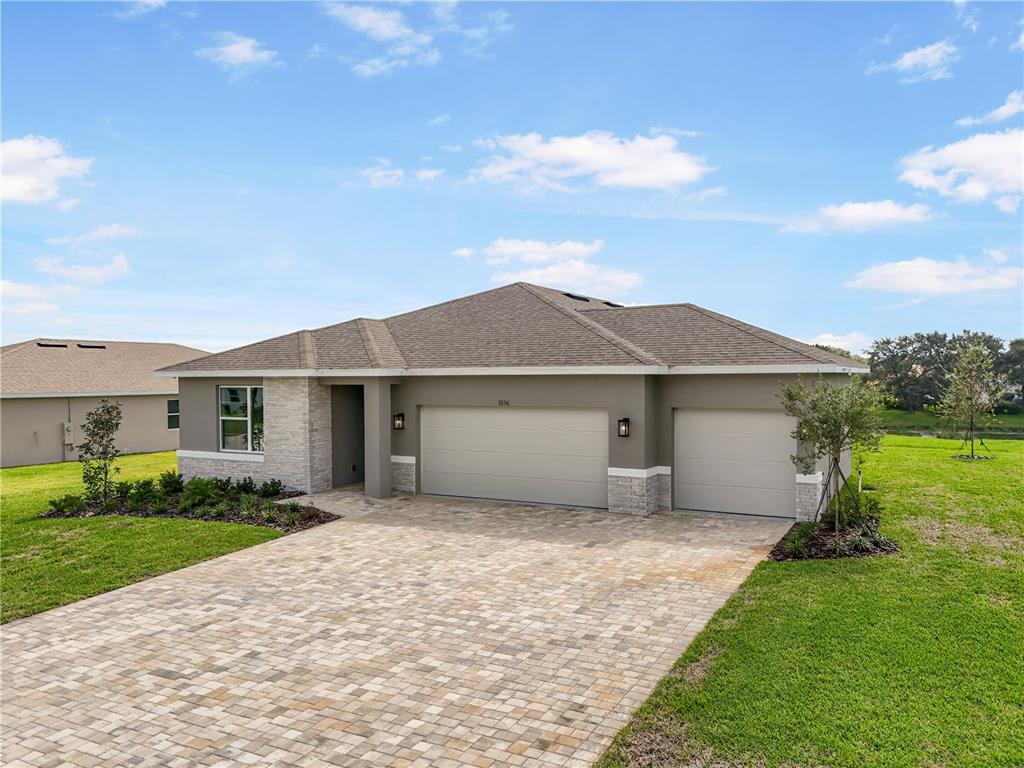 A single-story house with a paved driveway, two-car garage, and stone accents on the exterior — 9156 PLAYERS DRIVE, WEEKI WACHEE, FL