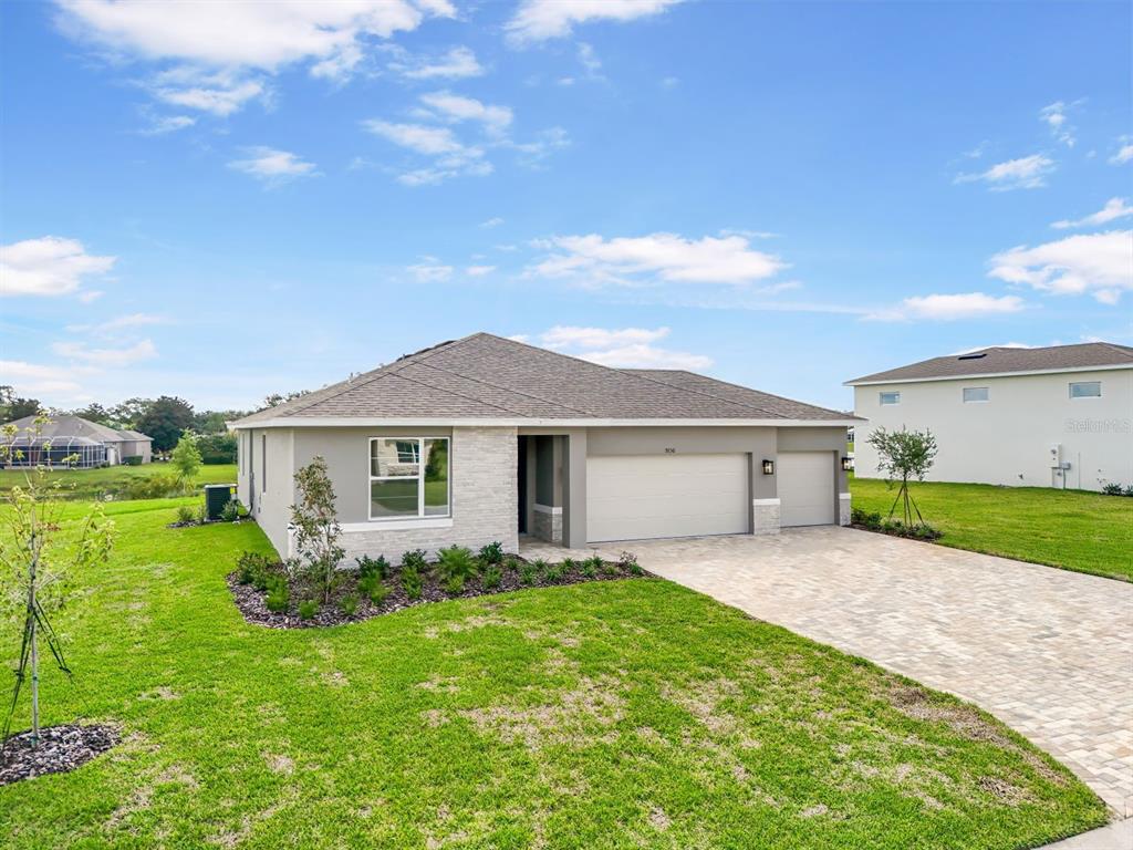 A single-story house with a stone facade, a paved driveway, and a three-car garage — 9156 PLAYERS DRIVE, WEEKI WACHEE, FL